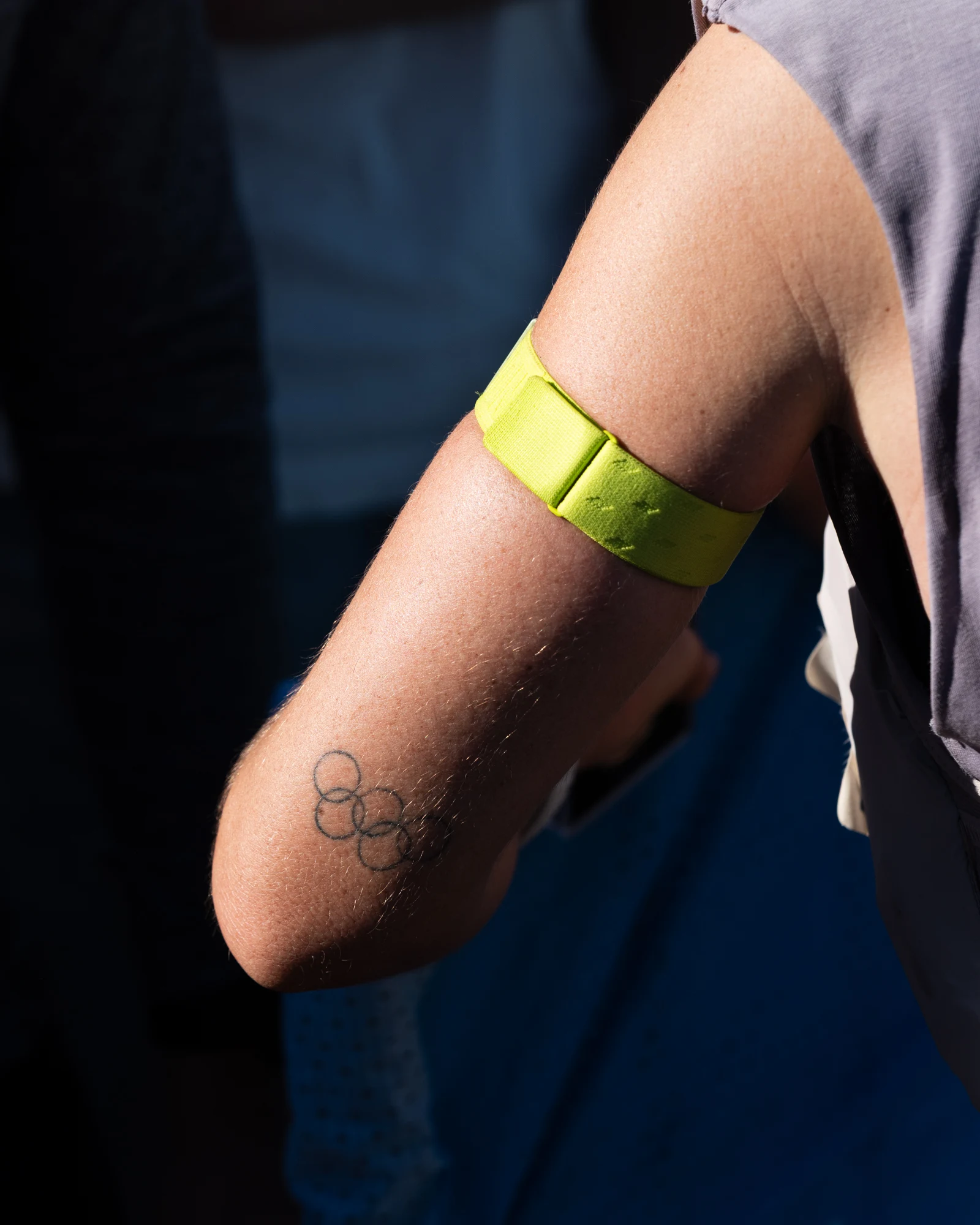 A close view of a neon race band above an Olympic rings tattoo on Molly Seidel's arm.