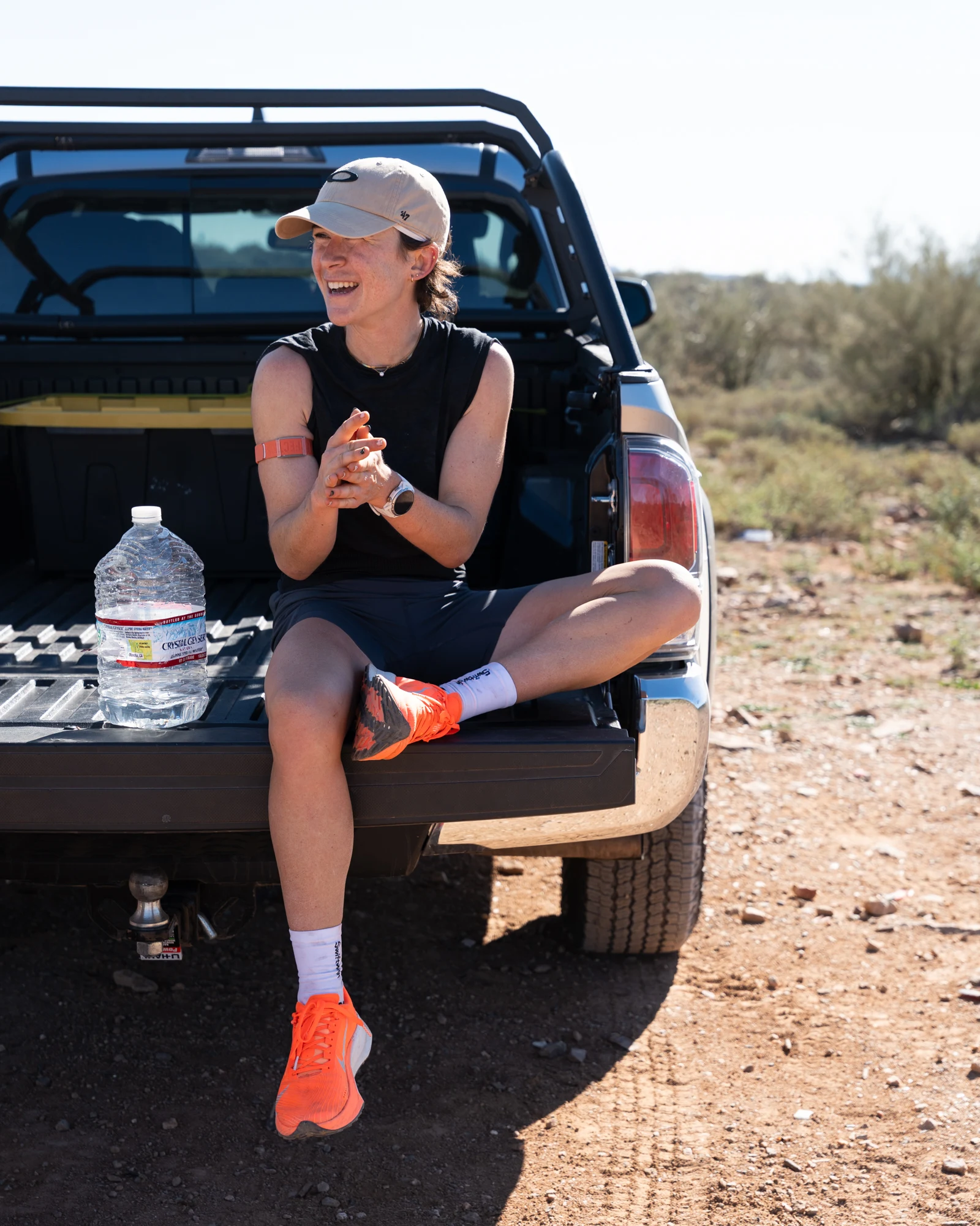 Molly Seidel smiles while sitting on an open tailgate during a desert aid stop.