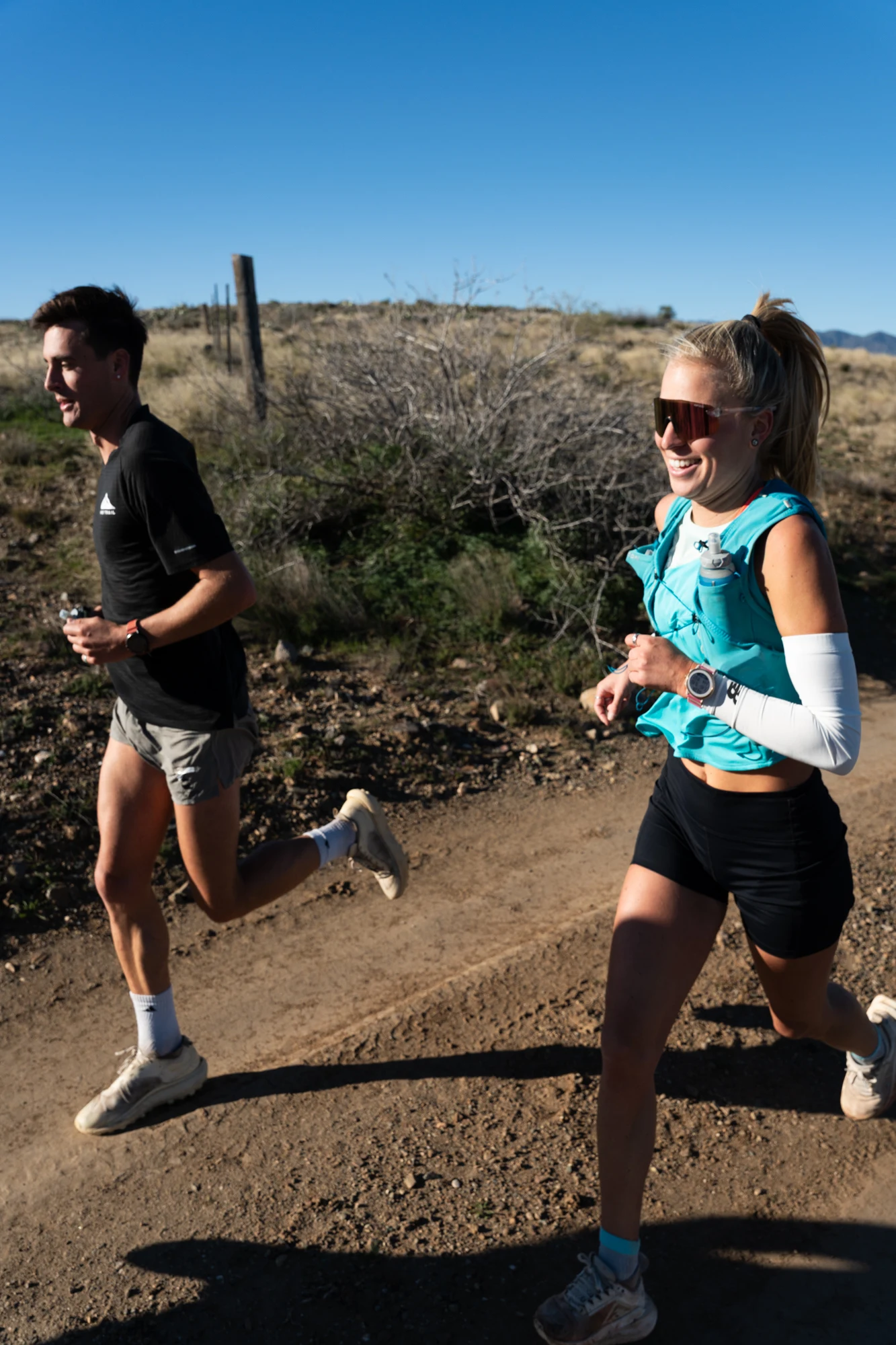 Two Ponderosa Pirates runners move side by side on a desert trail.