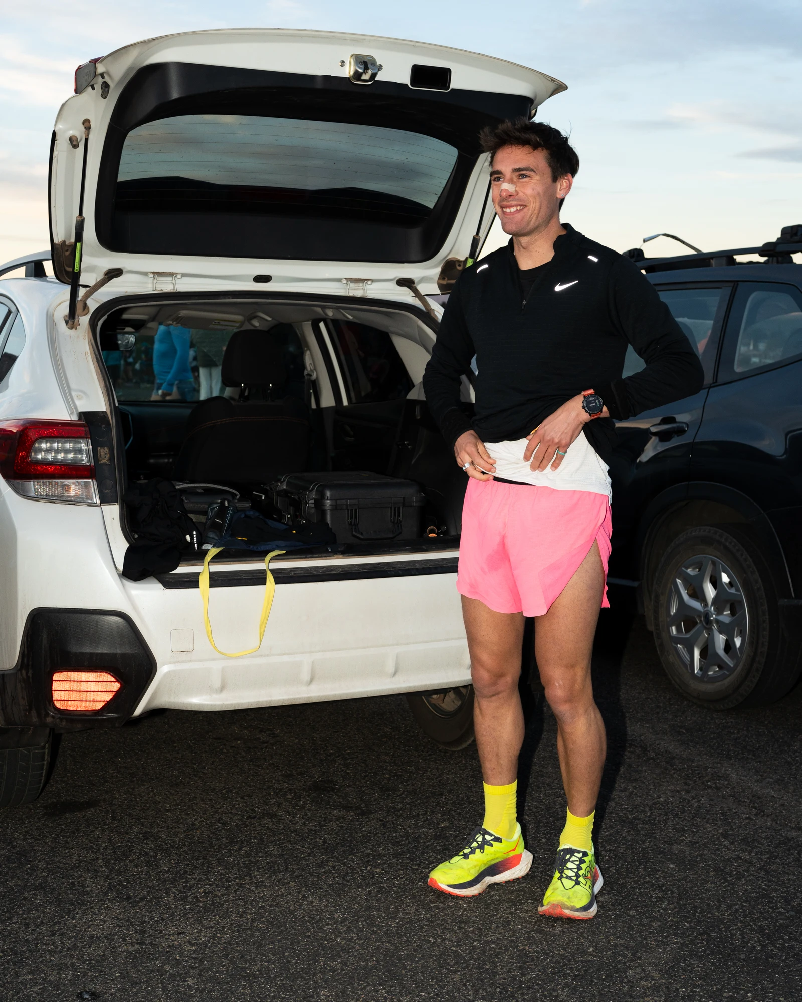 A Ponderosa Pirates runner stands beside an open support vehicle after a race.