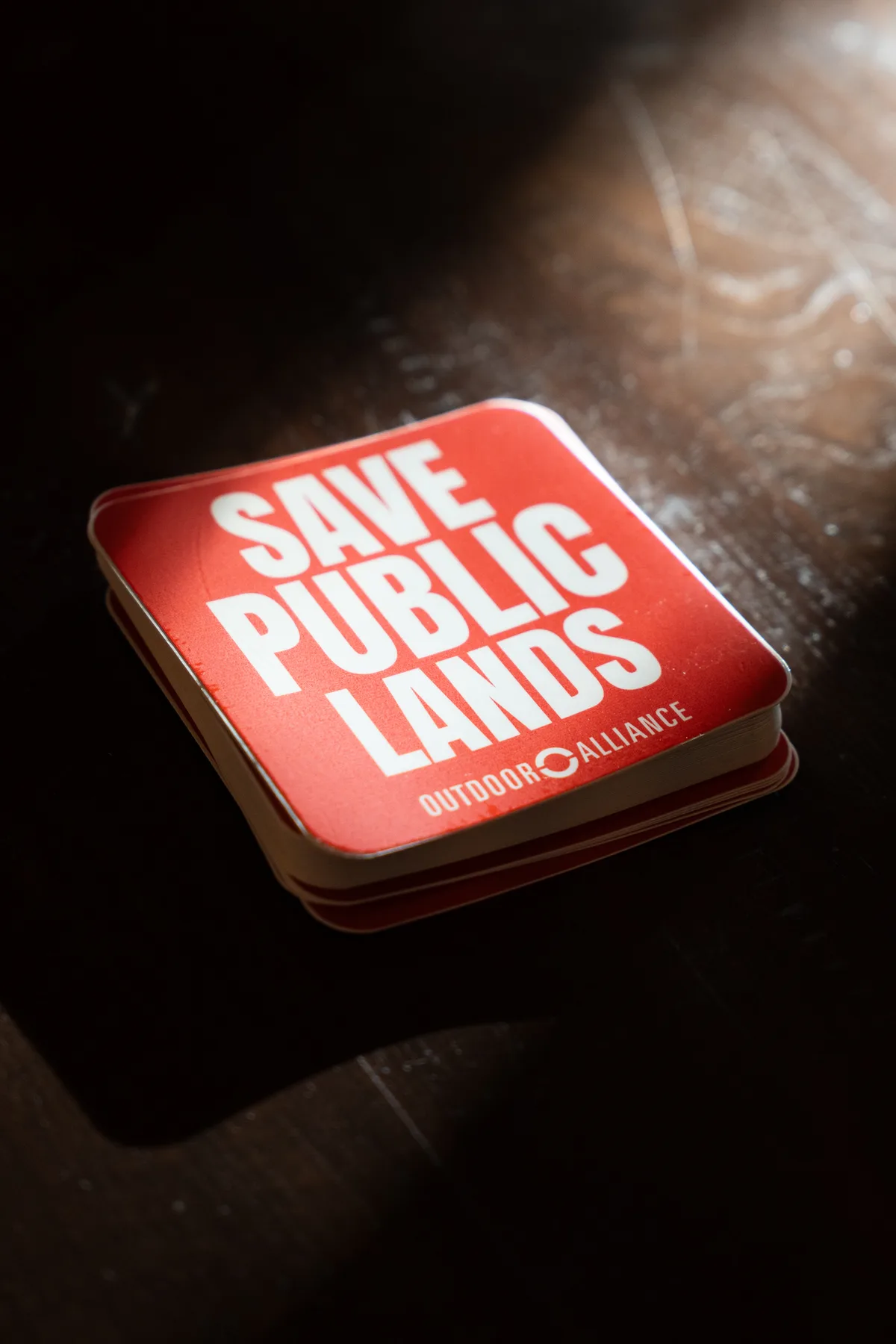 A red Save Our Public Lands patch rests on a dark surface.