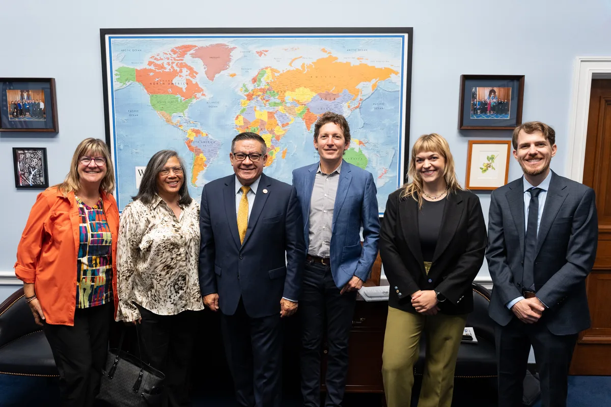 A group of advocates poses together in an office beneath a wall map.