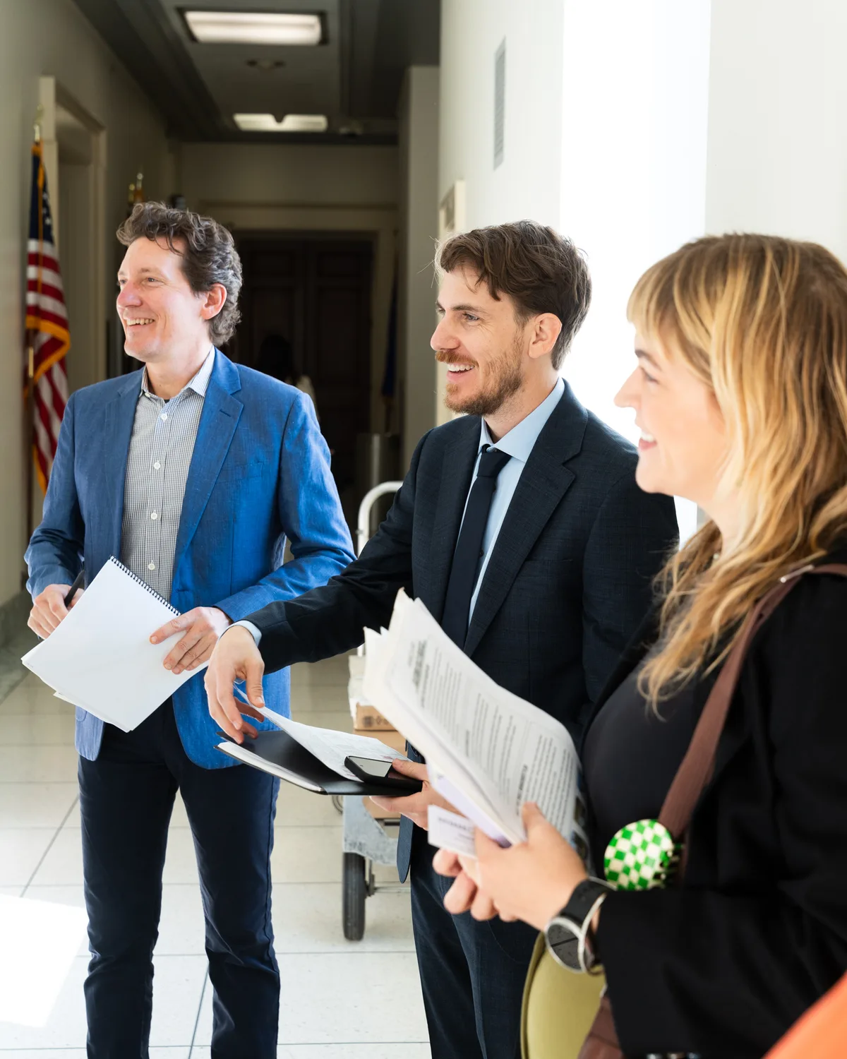 Advocates carry meeting papers through a corridor together.