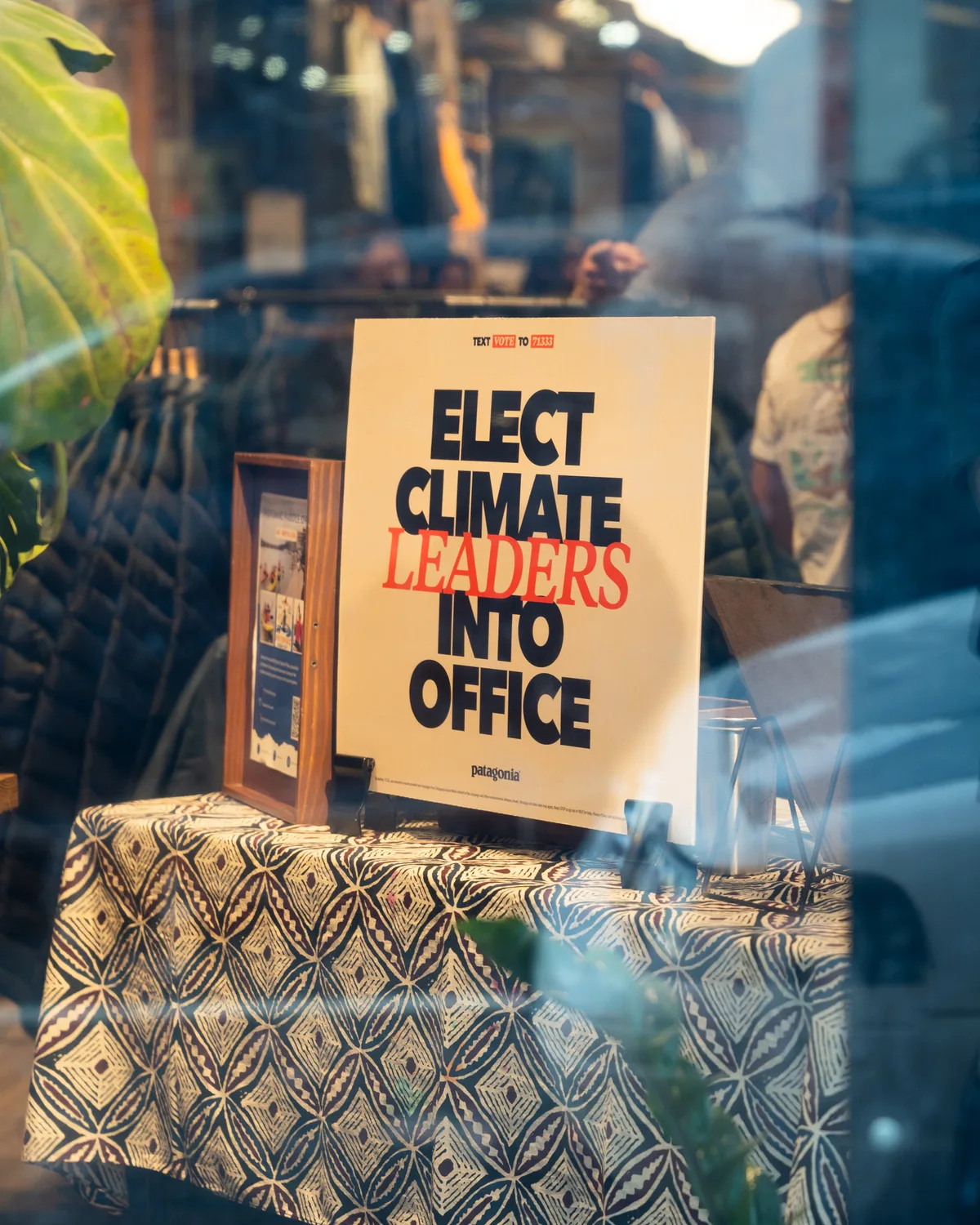 An Elect Climate Leaders Into Office sign stands in a shop window.