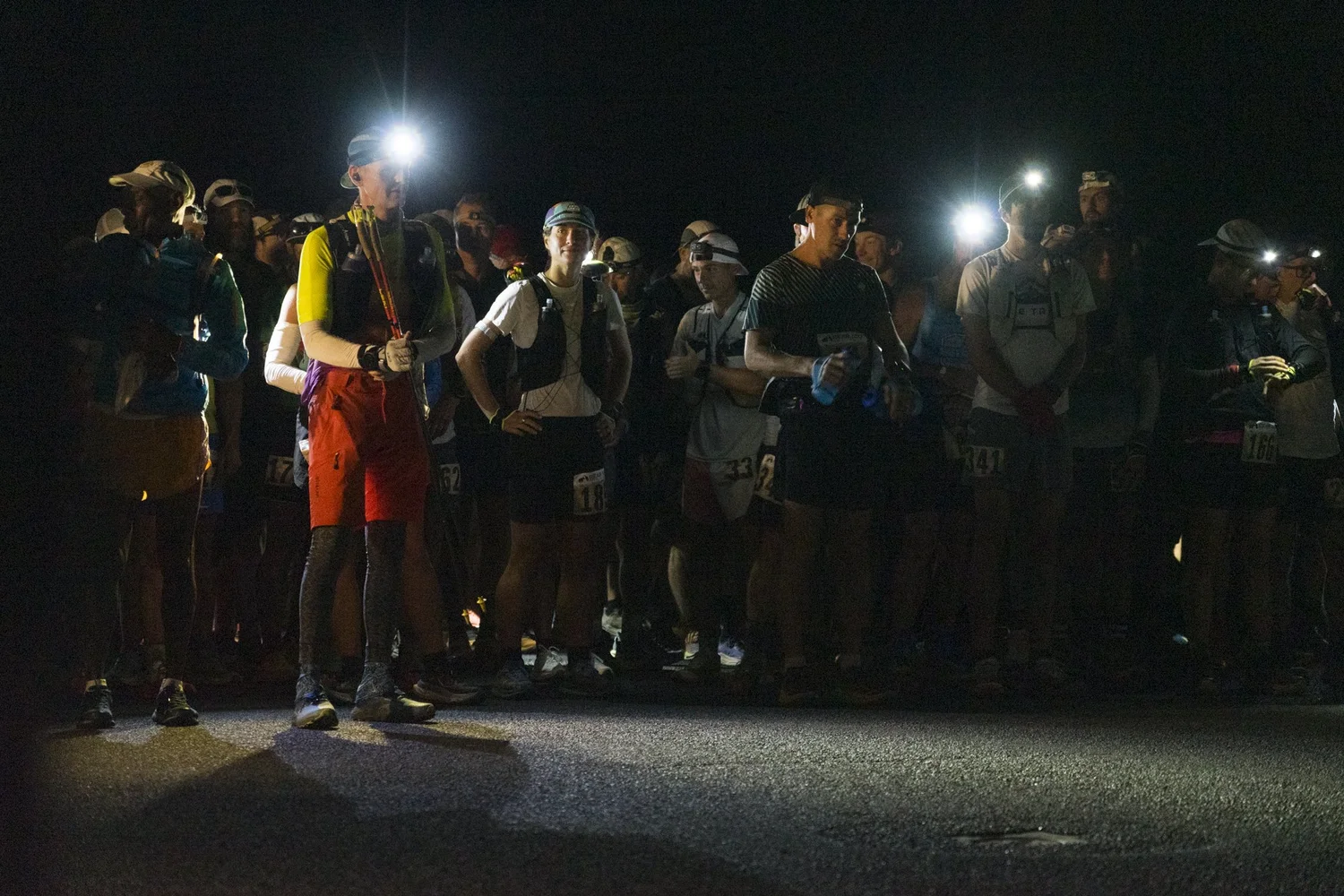 Bear 100 runners gather at the nighttime start with their headlamps illuminated.